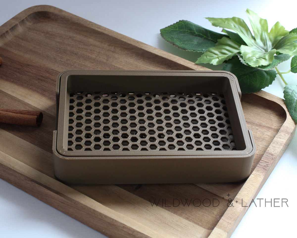 Dark Brown 3D printed soap dish on a wooden cutting board with cinnamon sticks and green leaves in the background