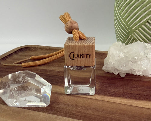 Clarity Glass diffuser with wooden tag on a wooden board with crystals and plants in the background