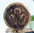 Wooden circular decoration with engraved design of Hecate and wolf on a stand.