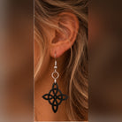 Close-up of a black Celtic knot dangle earring with silver fishhook finding, showing the intricate interwoven design and lightweight hanging style.